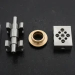 Precision CNC machined aluminum plate, stepped steel shaft on V-blocks, bronze bushing and cross-drilled block resting on black granite metrology plate