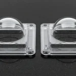 Two optically clear injection-molded polycarbonate industrial sensor dome housings with uniform walls on black granite