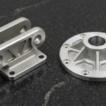 Lost-wax investment-cast 17-4PH stainless clevis yoke beside high-pressure die-cast ADC12 aluminum rotary flange hub