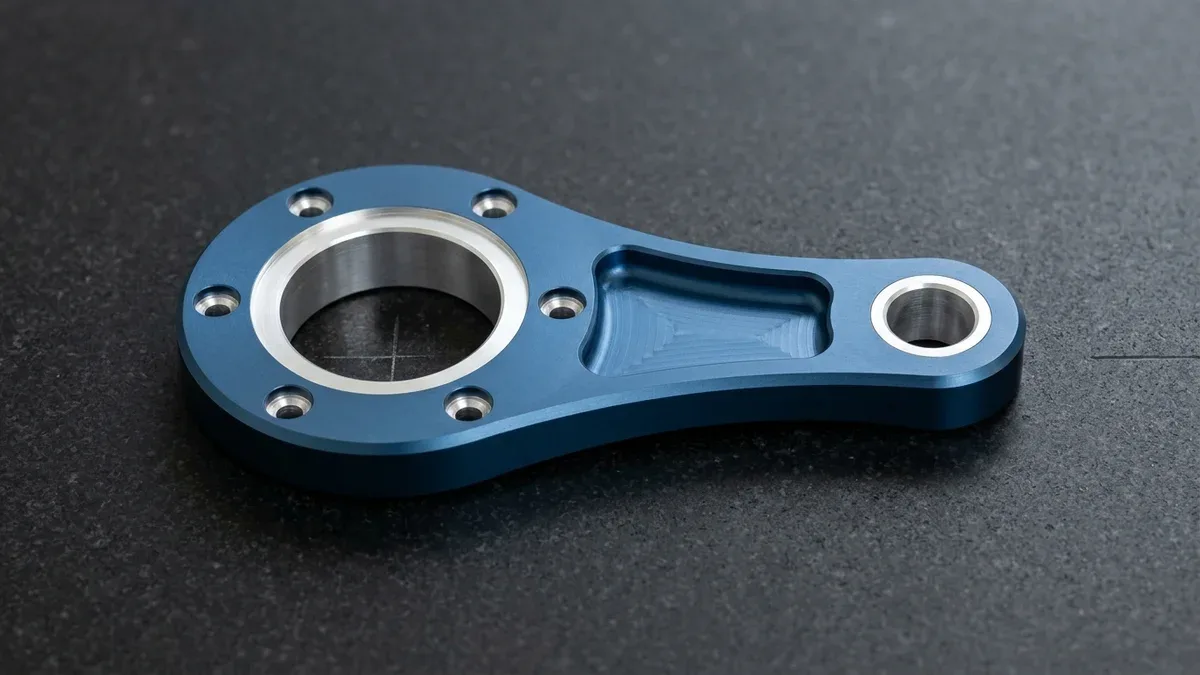 3-axis CNC-milled 6061-T6 aluminum twin-bore bearing carrier linkage plate with deep-blue anodizing and selectively masked bearing seats